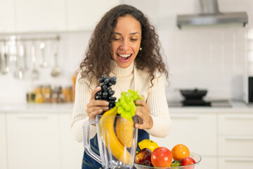 Latin woman making juice in kitchen