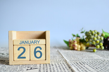 January 26, Calendar cover design with number cube with fruit on newspaper fabric and blue background.