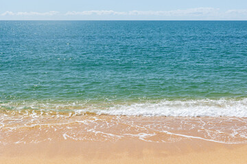 Turquoise sea waves splashing on sand shore