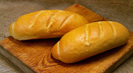 Two loaves of bread on a wooden cutting board.