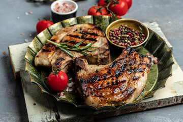 Grilled pork steak on the bone with seasonings and tomatoes. Food recipe background. Close up, top view