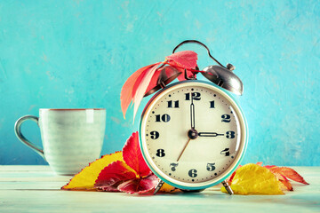 Daylight Saving Time concept, fall back in autumn. A vintage alarm clock with coffee and autumn...