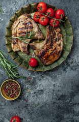 two pieces of of grilled pork with herbs on metal tray. Organic food. vertical image. top view. place for text