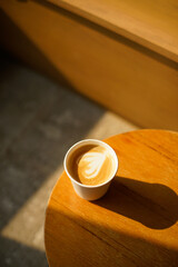 Cup of coffee with milk put on a chair in sunlight shade cafe with cozy room