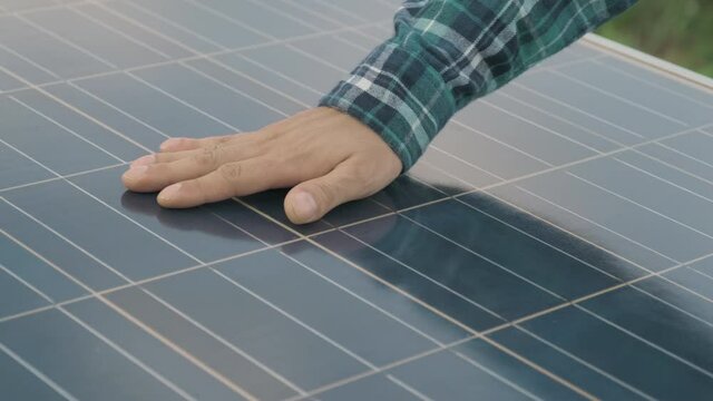 Close up hand of engineering man he's check an operation of sun and cleanliness of photovoltaic solar panels, man touching solar cell panels at sunset, Technician checking after install energy