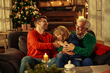 Adorable little boy relaxing on the sofa with his father and grandfather at home