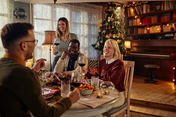 Cheerful friends having dinner together on Christmas eve at home