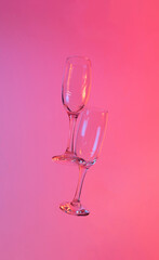 two glasses of champagne with neon pink lights. modern futurism 2022 year background. minimalism. surrealism. creative decoration idea
