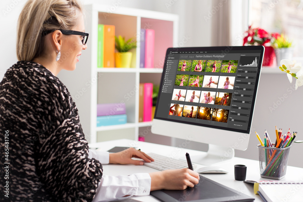 Wall mural woman working with digital photo library on desktop computer and editing photos