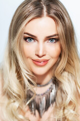 Naklejka premium A beautiful smiling blonde with bright blue eyes and long luxurious hair. An elegant, showy lady. White background. Close-up. Vertical.