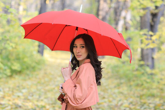 Beautiful woman with red umbrella in autumn forest