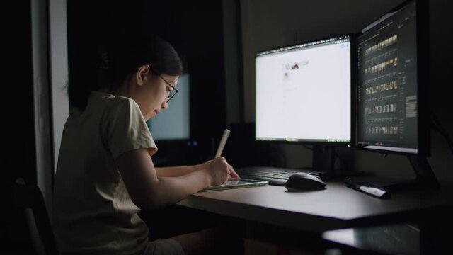 A young woman using a tablet at night in a home office, scrolling news feeds, and searching data of online information for her work plan.