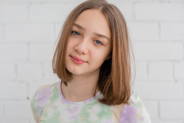 portrait of a slender teenage girl in a light turtleneck in natural light against a white brick wall. natural beauty, no makeup. problematic skin. space for text. High quality photo