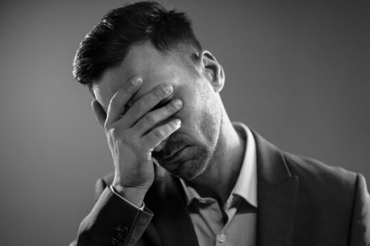 Tired Businessman After a Hard Day. Office Manager Touching His Face. Boss is Disappointed. Black and White Portrait. High quality photo
