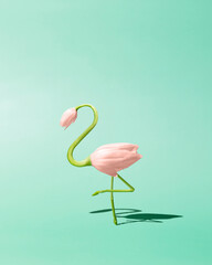 Contemporary art still life concept. Flamingo made from pink tulip flowers. Spring and summer green background. Flamingos Lover