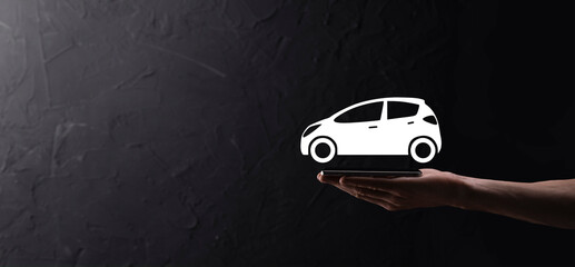 Male hand holding car auto icon on blue background. Wide banner composition.Car automobile insurance and collision damage waiver concepts