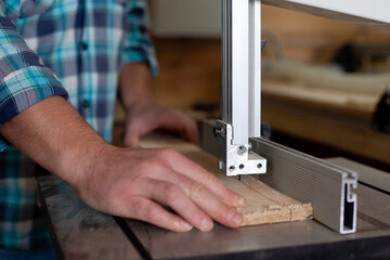  A carpenter in a plaid shirt works at a machine in a workshop. Wood. Ecological compatibility. Lifestyle. Close up