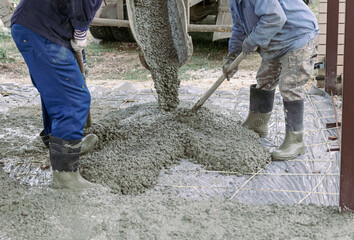 Workers level out the concrete mix at a construction site.