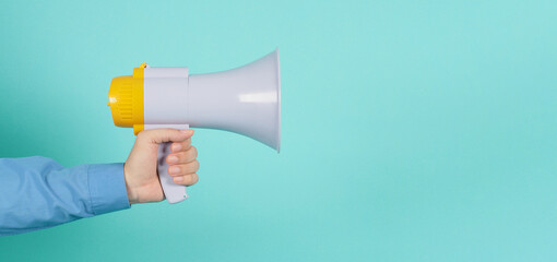 Hand is hold megaphone and wear blue long sleeve shirt on green mint or Tiffany Blue background..