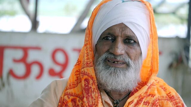 Indian saint sitting outside a temple. Indian Panditji wearing saffron cloth sitting - religious faith and beliefs