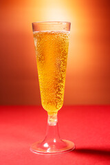 bubbly beer in plastic champagne glass on a pink and red background