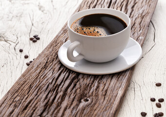 Cup of coffee americano and roasted coffee beans near the cup on the wooden table.