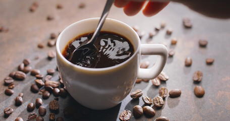 Cup of coffee americano and roasted coffee beans near the cup on the wooden table. Top view.