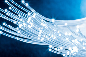 Bundle of optical fibers with lights in the ends. Blue background.