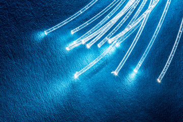 Bundle of optical fibers with lights in the ends. Blue background.