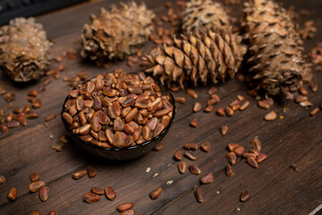 A pine cone and a walnut are lying on a wooden table