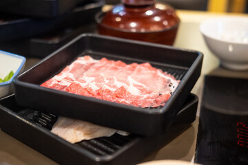Slice beef in black tray prepared for shabu or sukiyaki.