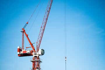 Red construction tower crane against blue sky