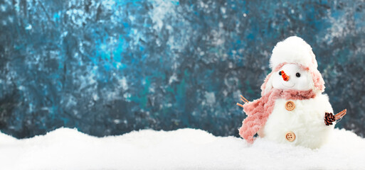 Christmas and new year snow concept with two cute snowmen in hats and scarves in snowdrift on blue background