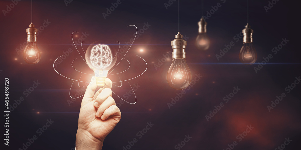Poster hand holding abstract light bulb on dark wide background with digital brain and atom outline and moc