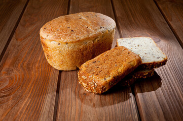 A loaf of delicious white bread made from natural products, on hops with flax saturation, without baker's yeast, on a wooden table surface.