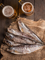 Two mugs of beer with dried fish on a table