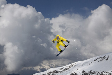A jumping snowboarder in the mountains. Snowboarding, winter extreme sport.