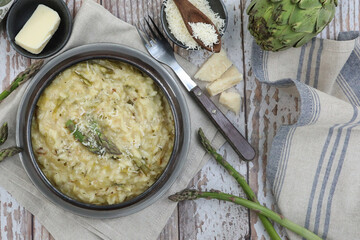 Italian risotto with spring asparagus, parmesan cheese and butter on rustic background
