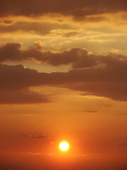 Vibrant sunset - sun surrounded by fluffy clouds