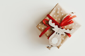 Christmas gift box wrapped in polka dot kraft paper decorated with red ribbon and wooden deer shaped ornament. Eco friendly gift wrapping idea