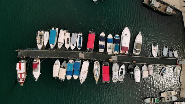 Drone top down view of marina harbor many colorful boats authentic ships fishing boats on shore near embankment of resort town. Marine vessels pattern. Top view harbor.