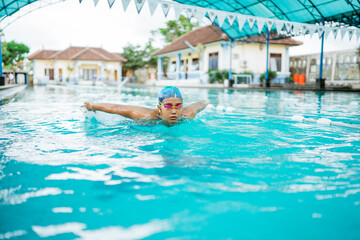 young female athlete in swimming goggles doing breaststroke and taking breath - obrazy, fototapety, plakaty