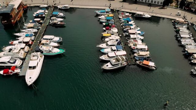 Resort seaside town promenade embankment, people tourists walking. Many beautiful multicolored motorboat boats on pier pettern top down view. Aerial top down view of sea dock with colorful boats. Top 