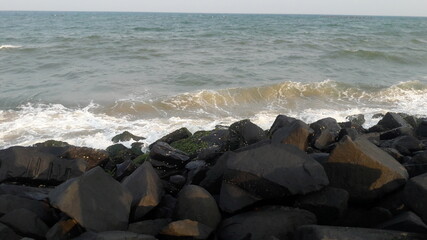Fototapeta na wymiar Rocks,stone and pebbles in goa beach with blue water and clear sky