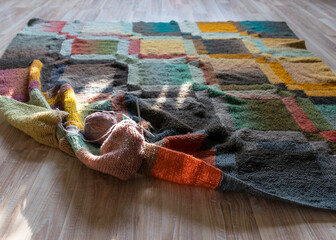 knitted quilt on the floor, sun toys on a plaid, entralact pattern, handmade, knitted background...
