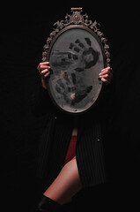 Girl holding a mirror with her hands. Costume on Halloween.