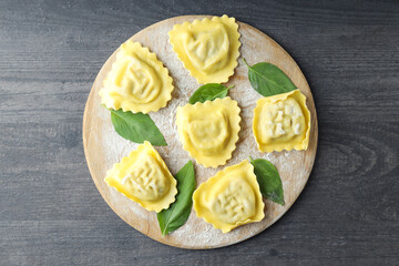Board with raw ravioli on dark wooden background