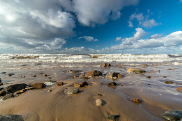 seascape with sea waves crashing on the shore and exploding, beautiful blue skies and white clouds over the sea, Vidzeme rocky seashore, Salacgriva rural area, Latvia