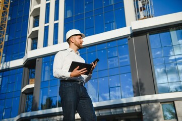 construction worker or architect in construction site outdoors with Hot weather sunny . builder in hard hat inspecting and working in workplace