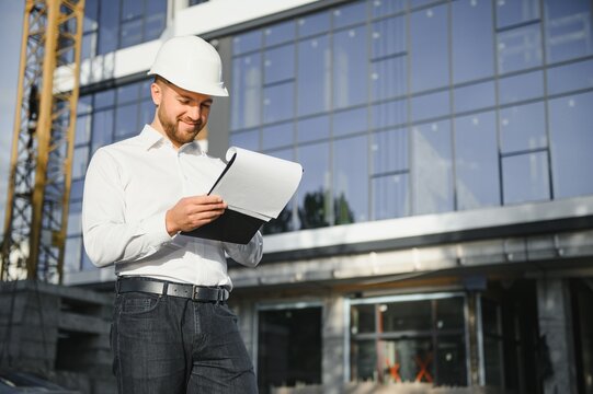 Architect In Helmet Writing Something Near New Building